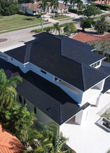 residential-roofers_florida Aerial view of a new dark roof on a two-story white home in a Florida neighborhood